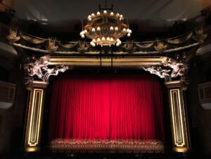 Sfeervol theaterpodium met gesloten rood fluwelen gordijn en kroonluchter