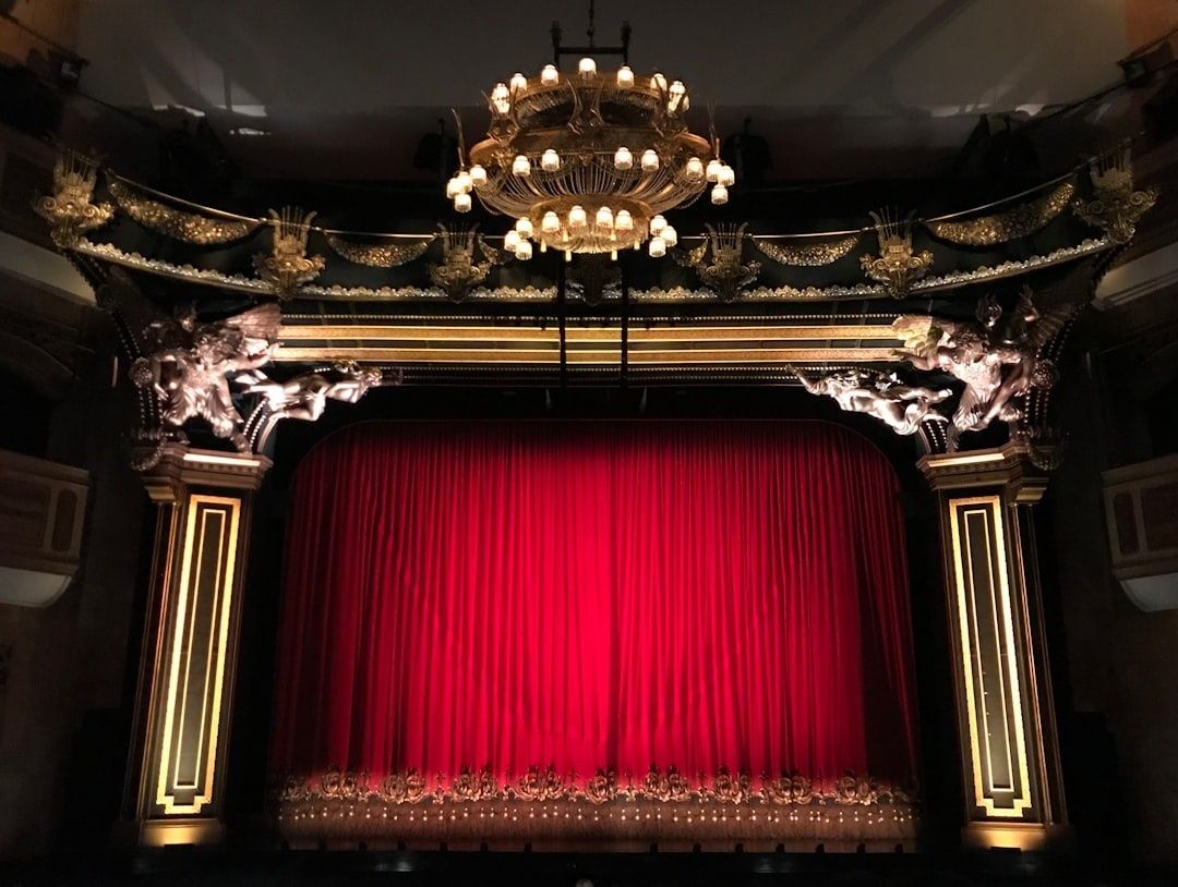 Sfeervol theaterpodium met gesloten rood fluwelen gordijn en kroonluchter
