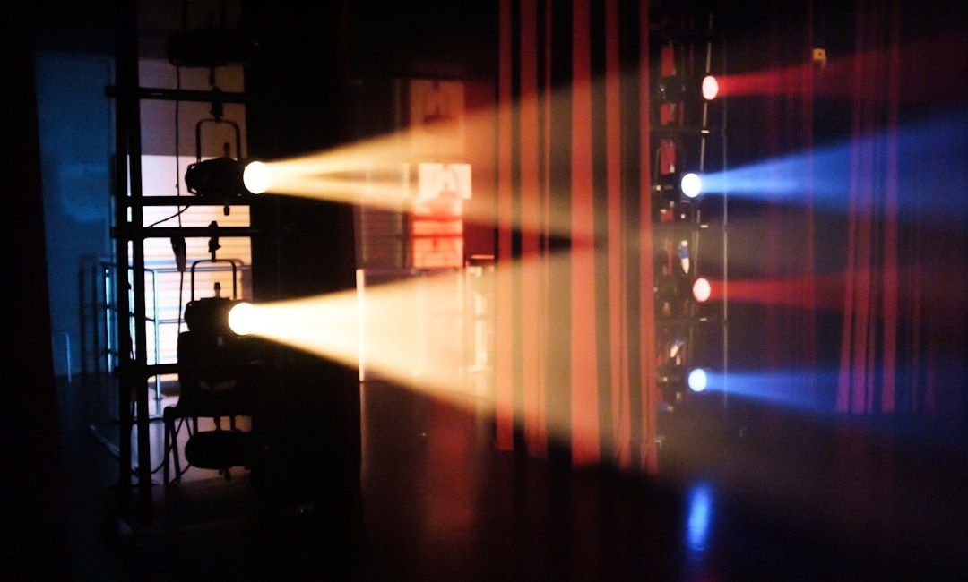Theaterlicht werpt rode, blauwe en warme lichtbundels achter de schermen