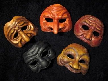 Vijf kleurrijke leren commedia dell’arte-maskers op een donkere ondergrond